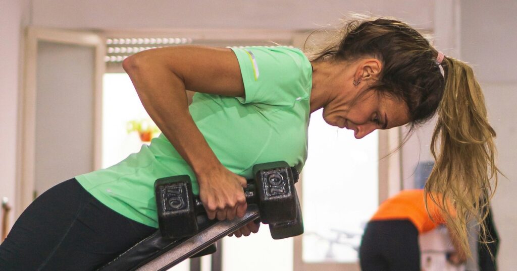 Woman in her forties doing a dumbbell row in a gym, protecting muscle during GLP-1 weight loss
