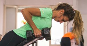 Woman in her forties doing a dumbbell row in a gym, protecting muscle during GLP-1 weight loss